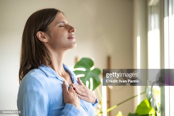 happy woman open window drapes close eyes in enjoy - main sur la poitrine photos et images de collection