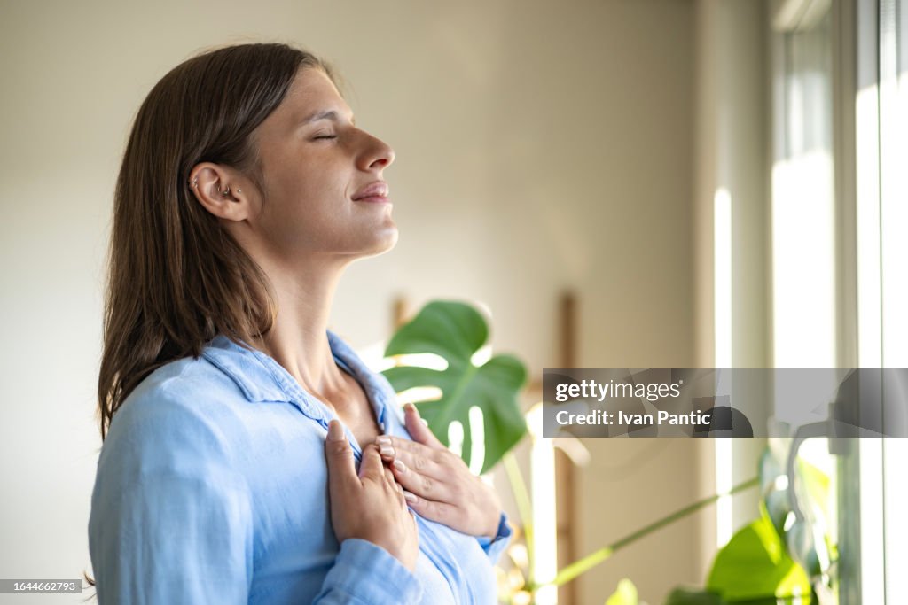 Happy woman open window drapes close eyes in delight