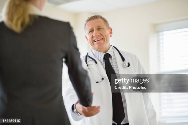 männlichen arzt und geschäftsfrau beim händeschütteln - handelsvertreter für medizinprodukte stock-fotos und bilder