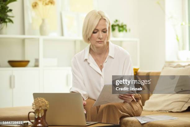 mature woman using laptop at home - cream colored shirt stock pictures, royalty-free photos & images
