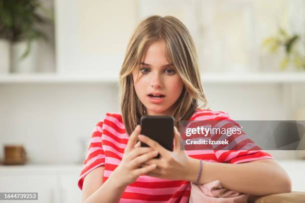 shocked teenage girl using smart phone at home - gasping stock pictures, royalty-free photos & images