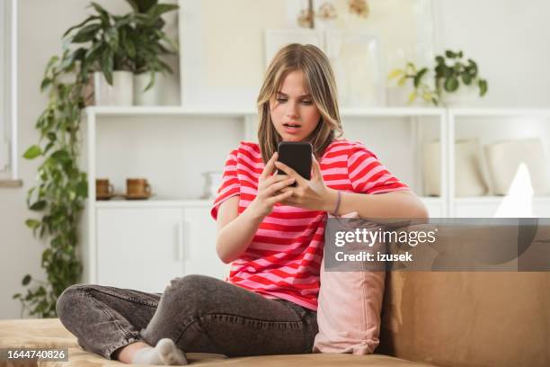 worried teenage girl using smart phone at home - bad news stock pictures, royalty-free photos & images