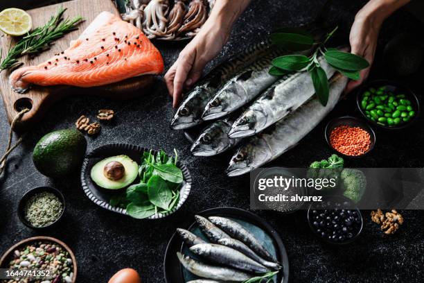 female hands arranging food ingredients with rich omega 3 and healthy fats - raw fish stockfoto's en -beelden