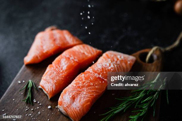 slices of salted salmon fish served with rosemary on wooden board - salmon steak stock pictures, royalty-free photos & images