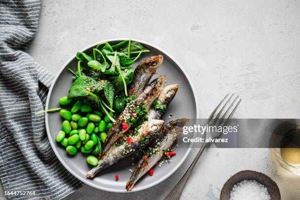 top view of spicy small fishes served on dinner table with green vegetables - omega 3 fish stock pictures, royalty-free photos & images