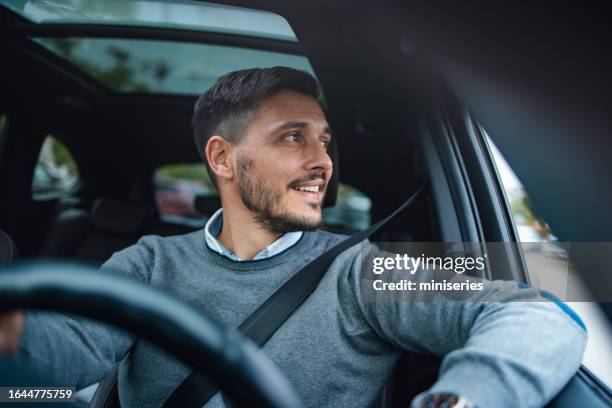 a happy handsome businessman looking away while driving his car - rush hour city cars stock pictures, royalty-free photos & images