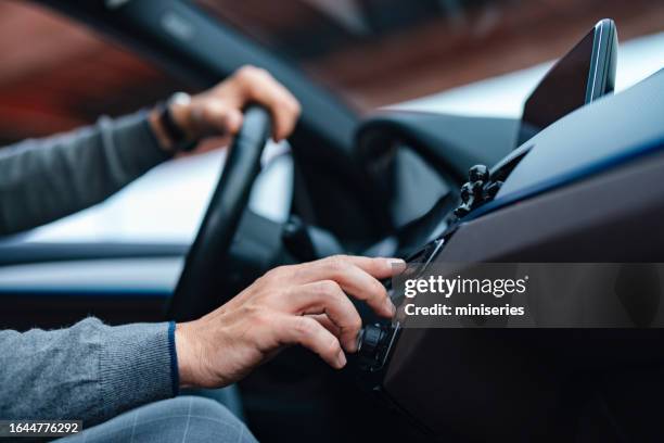 eine seitenansicht eines nicht wiederzuerkennenden geschäftsmannes, der während der fahrt sein radio einschaltet - car listening to music stock-fotos und bilder