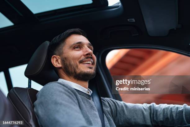 a happy handsome businessman looking away while sitting in his vehicle - carefree driving stock pictures, royalty-free photos & images