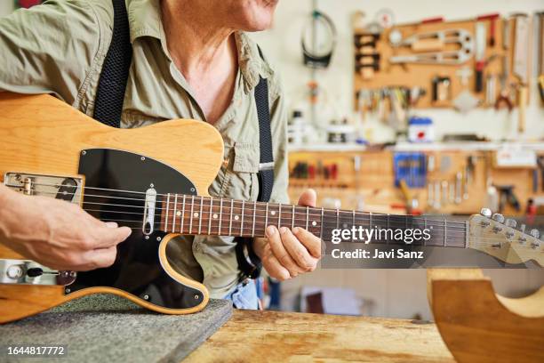 unrecognisable luthier man playing the guitar in his workshop. - instrument maker stock pictures, royalty-free photos & images
