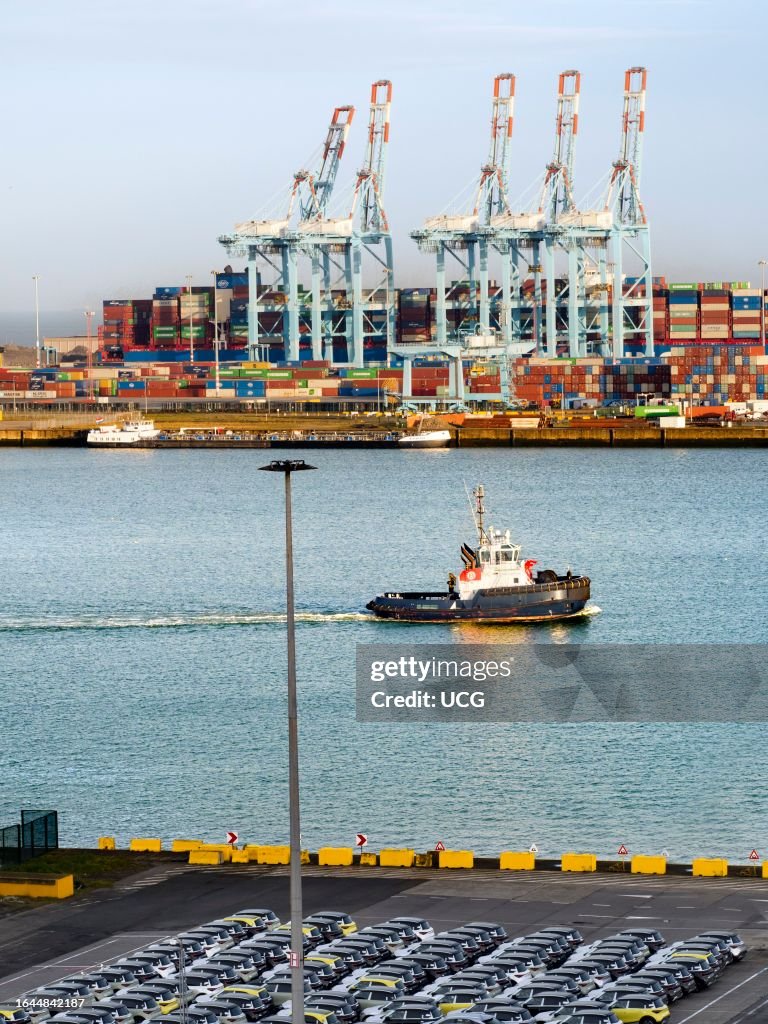Parked imported cars and gantry cranes on the quayside at Zeebrugge container port, Belgium