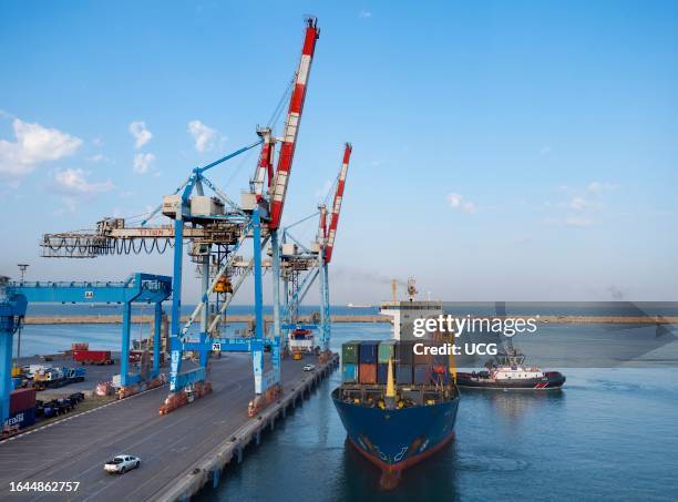 Giant gantry cranes and disembarking freighter seen from a cruise liner as it approaches the port of Ashdod, Israel.