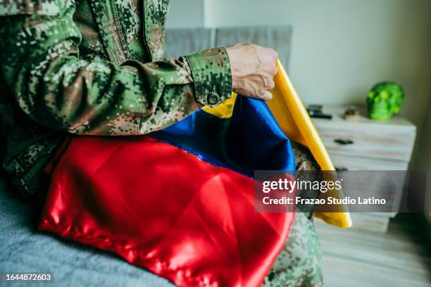 close-up of a soldier holding colombian flag at home - colombia pattern stock pictures, royalty-free photos & images