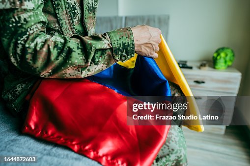 Close-up of a soldier holding Colombian flag at home Close-up of a soldier holding Colombian flag at home