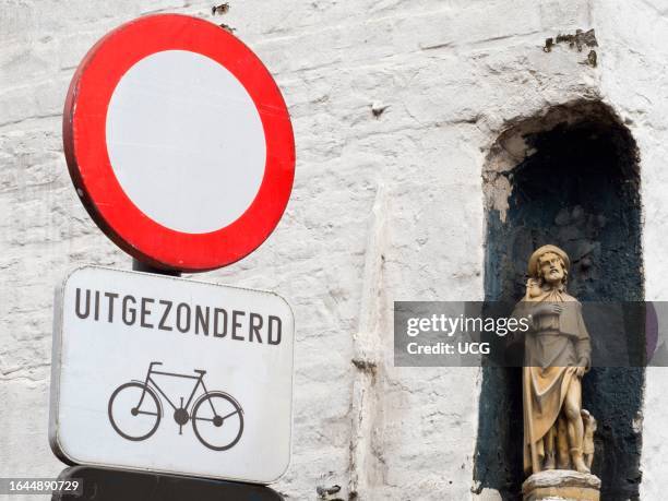 Road sign and statuette in Bruges, Belgium.