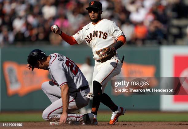 Thairo Estrada of the San Francisco Giants looks to throw to first base over the to of Matt Olson of the Atlanta Braves in the top of the fifth...