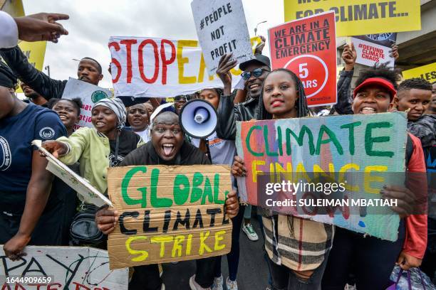 Climate activists hold placards and chant slogans as they take part in a march in Nairobi on September 4, 2023. The activists from various...