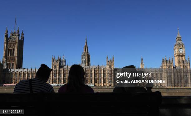 People look out across the River Thames at the Palace of Westminster, home to the Houses of Parliament - the House of Commons and House of Lords, in...