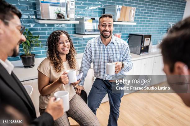 happy coworkers talking while drinking coffee at office - leisure work coffee happy stockfoto's en -beelden