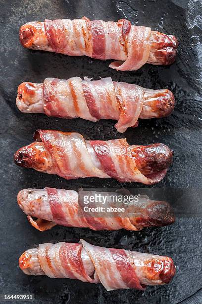 cooked pigs in blankets on slate surface - bacon isolated stock pictures, royalty-free photos & images