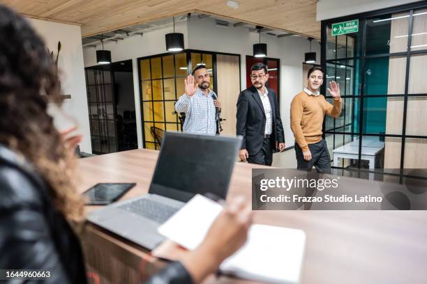 uomini d'affari che arrivano e salutano il collega alla reception dell'ufficio - sventolare la mano foto e immagini stock
