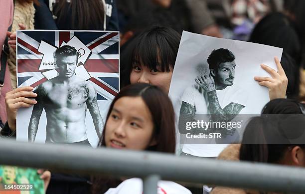 This picture take on March 23, 2013 shows fans holding posters of football superstar David Beckham in a stadium in Wuhan, central China's Wuhan...