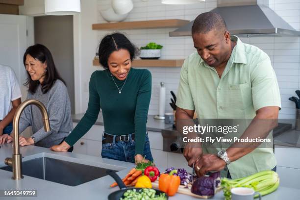 mixed race family cooking dinner together - 16 17 years stock pictures, royalty-free photos & images