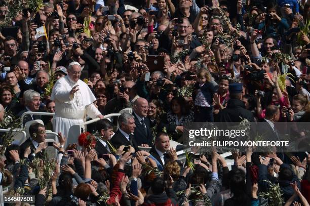 Pope Francis waves to the crowd from the papamobile after a mass on St Peter's square as part of the Palm Sunday celebration on March 24, 2013 at the...