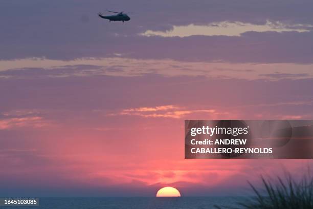 Presidential support helicopter passes over the ocean at sunrise as it comes in to land to pick up US President Joe Biden at Gordons Pond in Rehoboth...