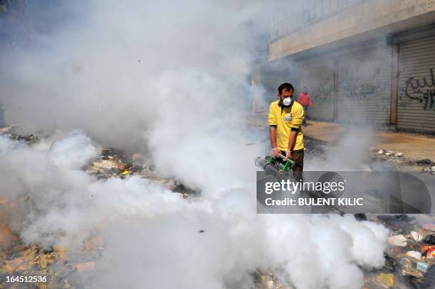 Syrian man fumigates a street covered with uncollected garbage in the northern city of Aleppo on March 24, 2013. Syria's mainstream insurgent Free...