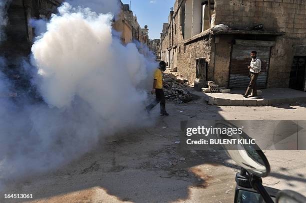 Syrian man fumigates a street covered with uncollected garbage in the northern city of Aleppo on March 24, 2013. Syria's mainstream insurgent Free...