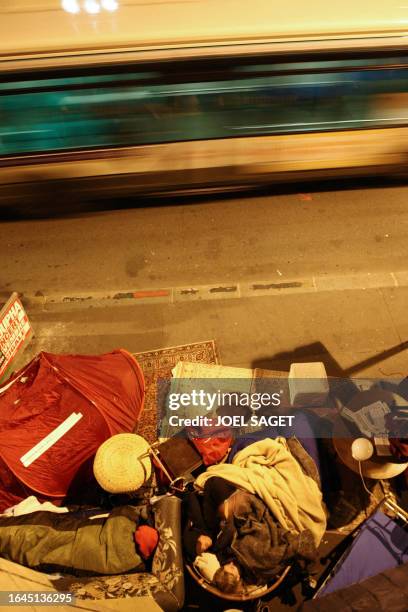 Young couple who came to support the homeless people demonstration, sleeps in the street as a bus drives, 24 October 2007 at Bourse's square in...