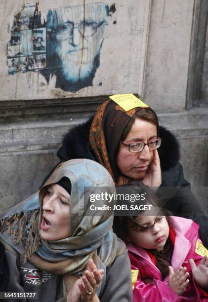 Homeless people sit under a portrait of deceased anti-poverty campaigner Abbe Pierre during a homeless demonstration rue de la Banque in Paris, 11...