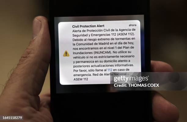 This photograph taken on September 4, 2023 in Madrid shows an alert in Spanish sent on September 3 by the Spanish Civil Protection displayed on a...