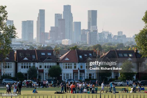 Community of park users and suburban residential properties with distant city high-rises seen from Ruskin Park, a public green space in Lambeth, on...