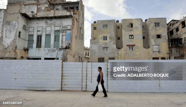 Woman walks past a ruined building in Havana on July 15, 2008. According to reports from the Government, the plan for construction and maintenance of...