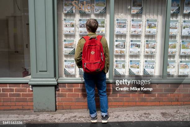 Woman looking in the window of an estate agent in Kings Heath on 6th August 2023 in Birmingham, United Kingdom. Housing in Birmingham is a very...