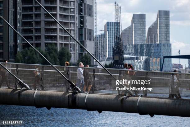 People and workers crossing the South Quay Footbridge in the heart of Canary Wharf financial district as new apartment high rise buildings can be...