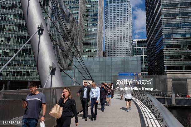 People and workers crossing the South Quay Footbridge in the heart of Canary Wharf financial district on 15th August 2023 in London, United Kingdom....