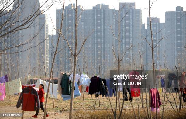 Woman walks past the strings of drying laundry in front of the apartment buildings in Beijing on March 28, 2011. China's efforts to cool its red-hot...