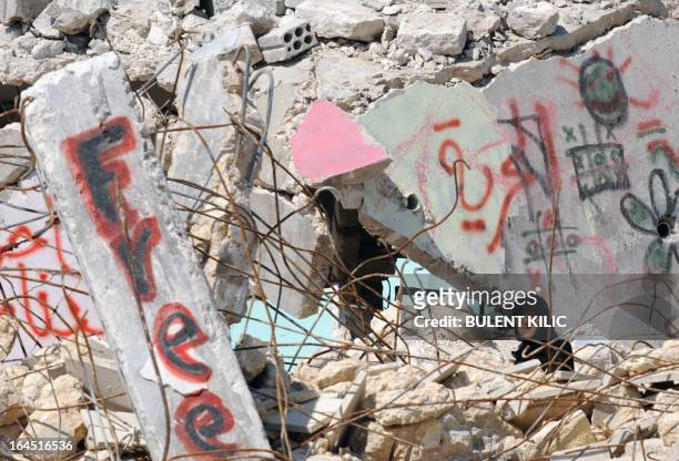 Syrian woman walks past destroyed buildings in the northern city of Aleppo on March 24, 2013. Syria's mainstream insurgent Free Syrian Army does not...