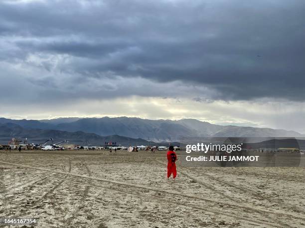 Attendees walk through a muddy desert plain on September 3 after heavy rains turned the annual Burning Man festival site in Nevada's Black Rock...