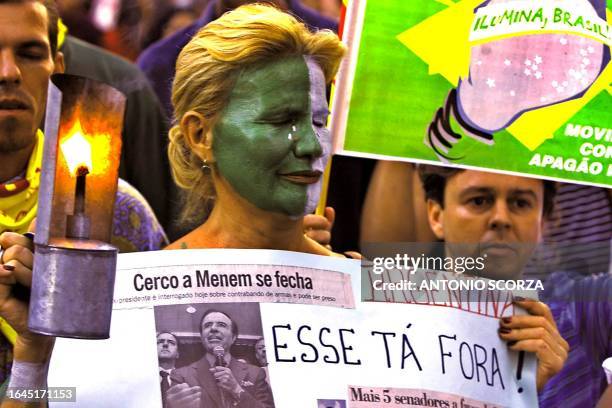 Woman shows a poster relating to the arrest of former Argentine President Carlos Menem, during a protest, 12 June 2001, against corruption and energy...