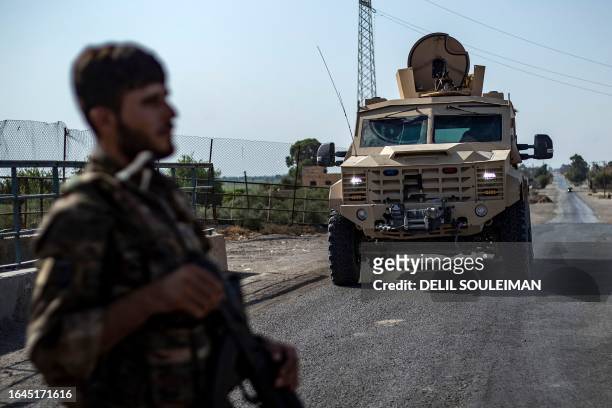 Fighter of the Syrian Democratic Forces stands guard along a road as others deploy to impose a curfew in the town of al-Busayrah in Syria's...