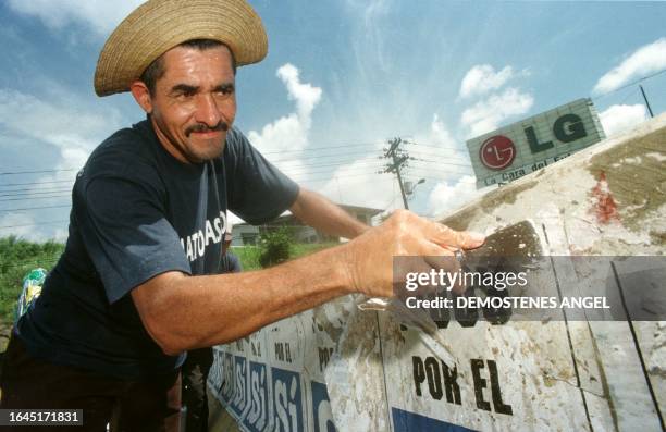 Panamanian worker Fidel Castro cleans referedum propoganda off of a bridge 02 September in Panama City in preparation for the 12th Summit of the...
