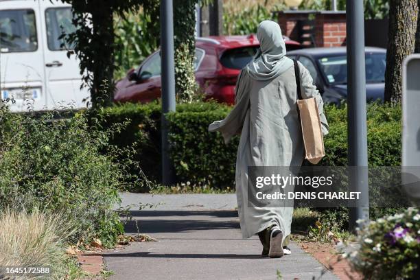 Woman wearing an abaya dress walks through the streets of Lille, northern France, on August 28, 2023. The French government's decision to ban...