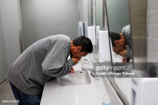 Jimmy Arias from Venezuela, washes his face in the bathroom of a makeshift shelter operated by the city at O'Hare International Airport on Aug. 31,...