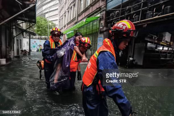 This photo taken on September 4, 2023 shows rescue personnel evacuating a woman in a flooded area from heavy rains caused by Typhoon Haikui in...