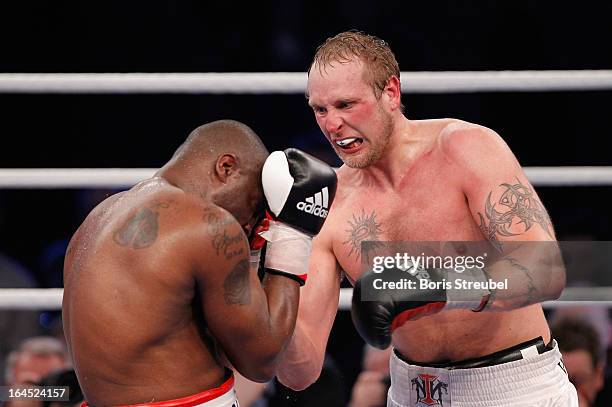Michael Sprott of Great Britain and Robert Helenius of Finland exchange punches during the Heavyweight fight at Getec Arena on March 23, 2013 in...