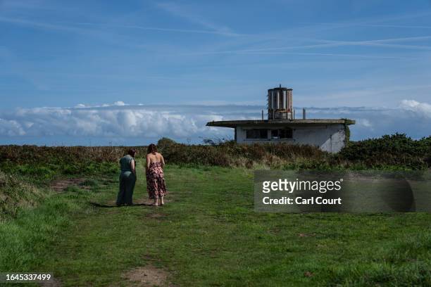 Women pause next to a building in what was once Lager Sylt Nazi concentration camp, one of four camps that were built on Alderney during World War...
