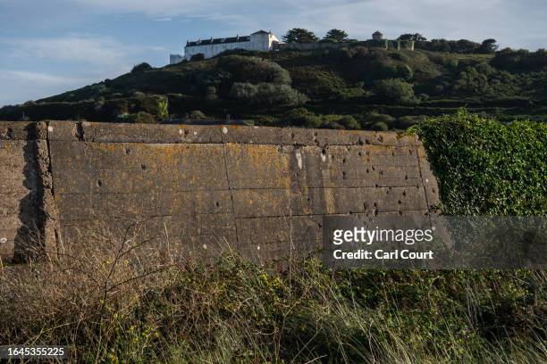Bullet holes where prisoners were executed pierce parts of Longis anti-tank wall, a 6-meter tall concrete wall built by forced labour under German...